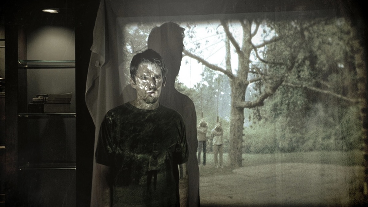 Ethan Hawke se para frente a una pantalla donde se proyecta un asesinato grizzly en Sinister: películas y programas como Archive 81