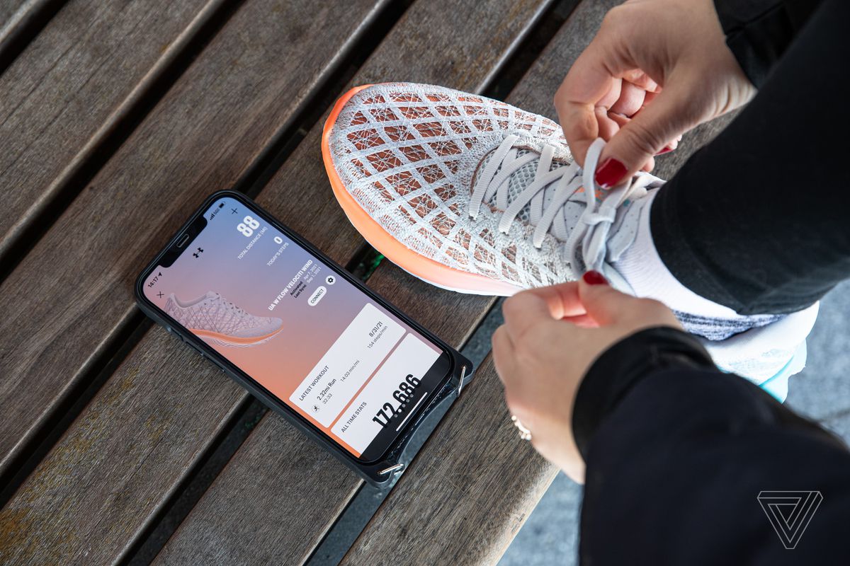 Persona atándose un zapato junto a un teléfono con la aplicación MapMyRun levantada