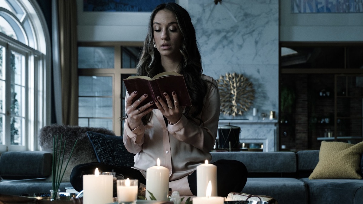 Una mujer lee un libro antiguo rodeada de velas en The Magicians - muestra como sus materiales oscuros